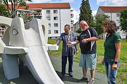 Zwei Männer und eine Frau stehen an einer Beton-Rutsche in Form eines Elefanten.