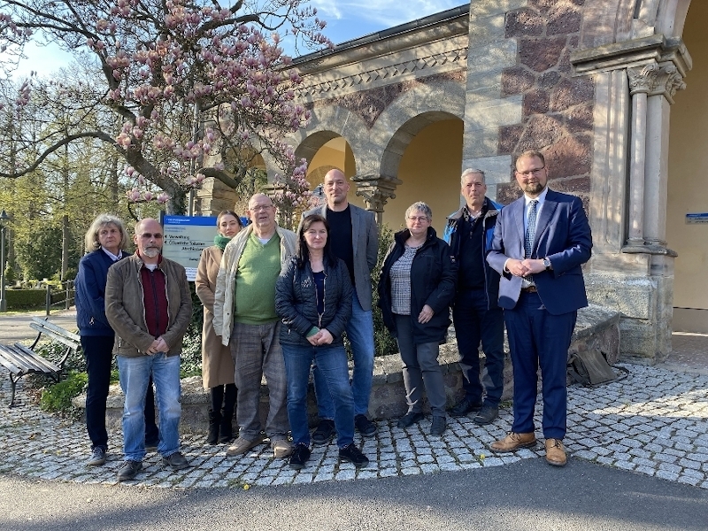 Eine Menschengruppe steht vor der Friedhofskapelle.
