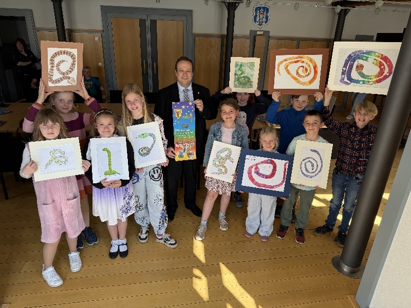 Mehrere Kinder zeigen ihre Schlangenbilder. Außerdem hält ein Mann ein Plakat in den Händen.