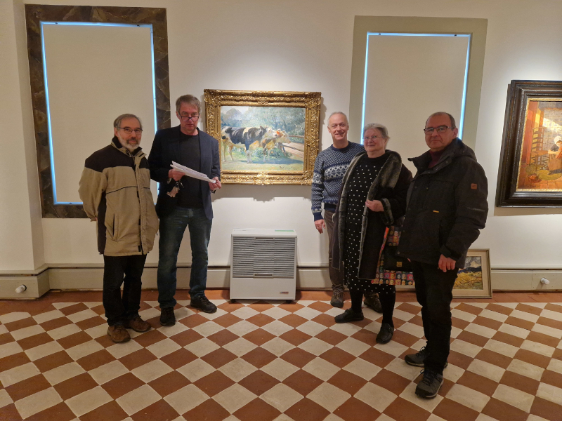 Vier Männer und eine Frau stehen in einer Galerie. Im Hintergrund ist ein Bild zu sehen, das Rinder zeigt.
