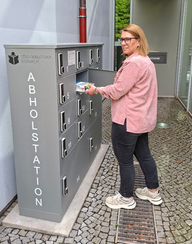 Eine Frau befüllt die Abholstation der Bibliothek.