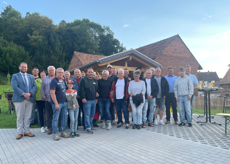 Etwa 30 Männer und Frauen stehen auf einem gepflasterten Platz.