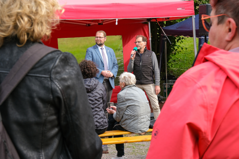 Zwei Männer stehen unter einem Festzelt und reden.