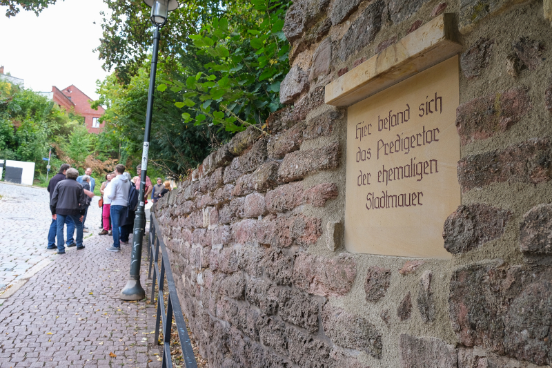 In eine alte Stadtmauer ist eine Tafel eingearbeitet. Sie weist auf das frühere Predigertor hin.