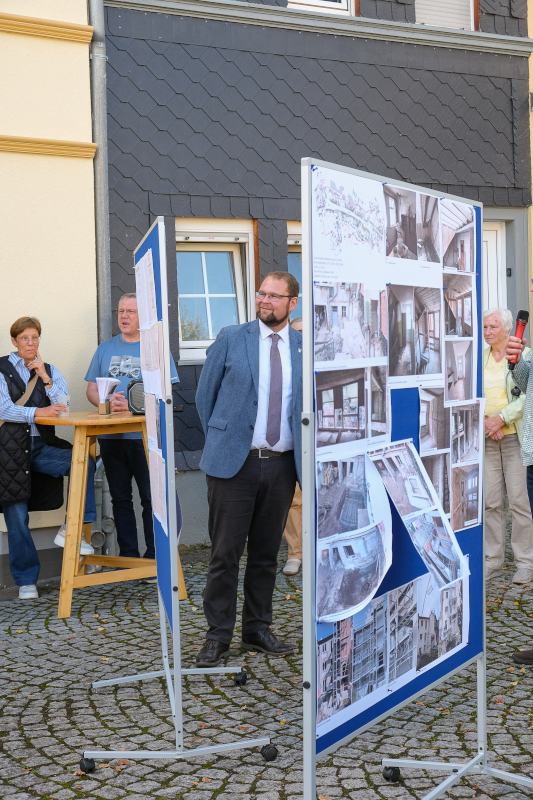 Zwischen zwei Info-Tafeln steht ein Mann im Anzug und schaut interessiert..