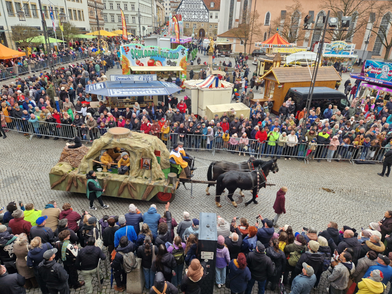 Ein Festwagen fährt durch eine Menschenmenge.