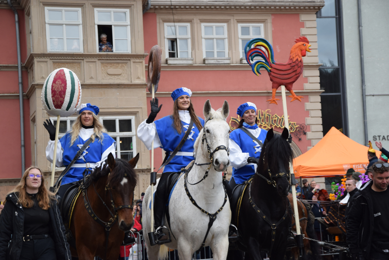Auf Pferden reiten die Symbole des Sommergewinns: Ei, Hahn und Brezel