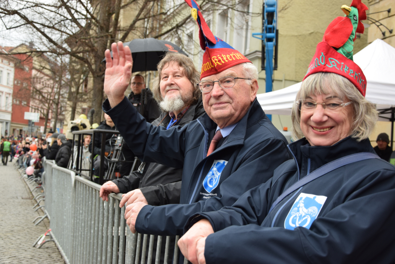 Zwei Männer und eine Frau stehen am Zaun und winken.