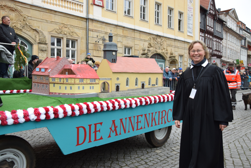 Auf einem Wagen steht ein Modell der Annenkirche. Daneben steht eine Frau in einem Talar (Pfarrerin).