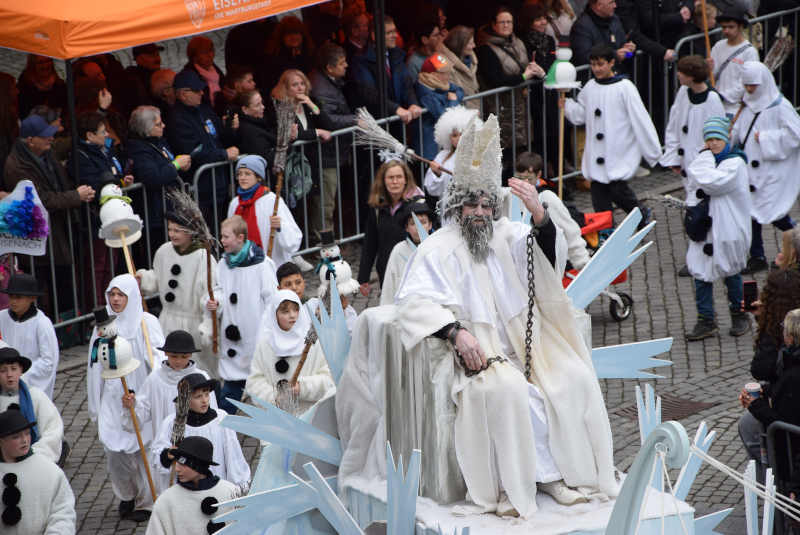 Ein als Winter verkleideter Mann fährt auf einem Wagen.