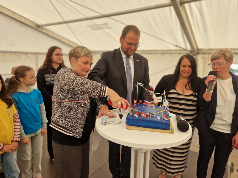 Ein Mann und eine Frau schneiden eine Torte an, die wie eine Europafahne aussieht. Daneben stehen zwei weitere Frauen.