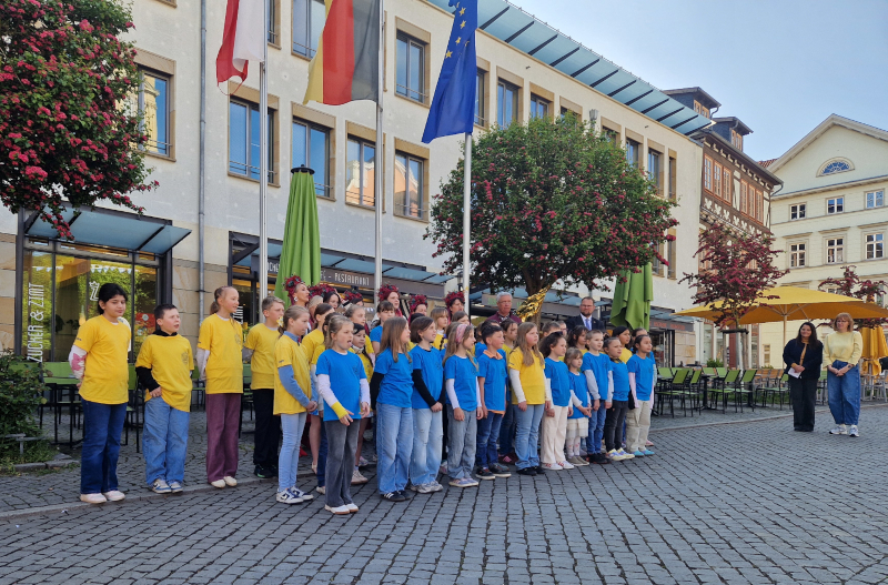 Kinder in blauen und gelben T-Shirts stehen vor Fahren.