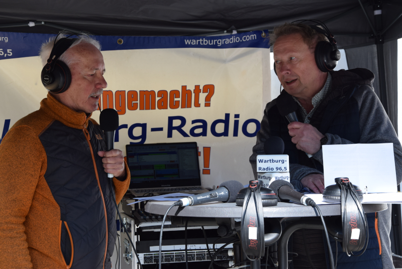 Zwei Männer mit Kopfhörern an einem Stand