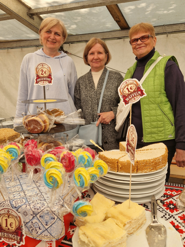 Frauen stehen hinter einem Kuchenbuffett