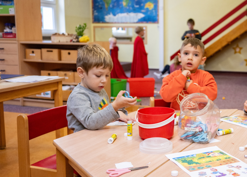 Zwei Jungen sitzen an einem Tisch und basteln mit Scheren.
