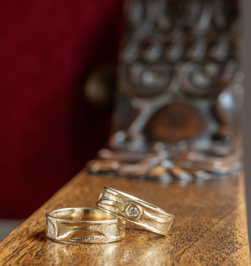 Zwei Eheringe - einer mit Edelstein - auf einem Holztisch