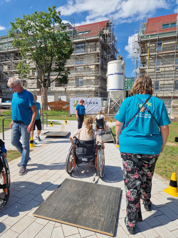 Mehrere Kinder in Rollstühlen testen den Rollstuhlparcour mit Begleitpersonen.